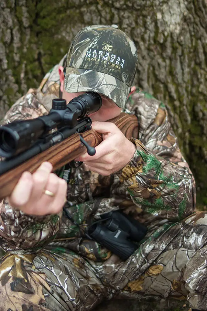 Man wearing camo shooting with a Bushnell Rifle Scope