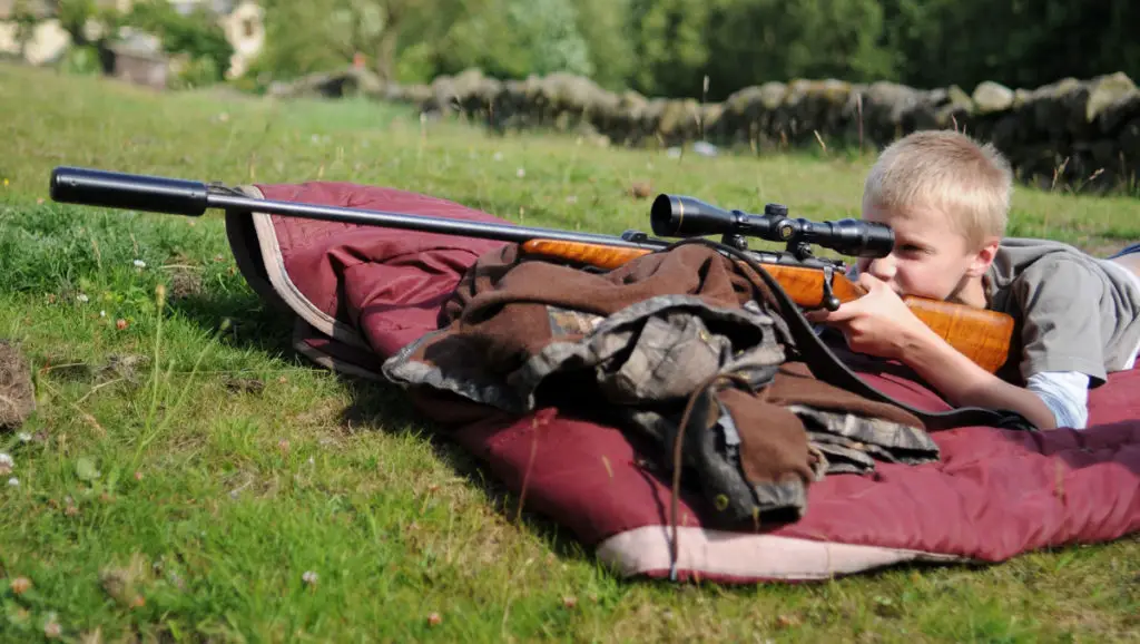 Young boy shooting a 22 rifle laying down