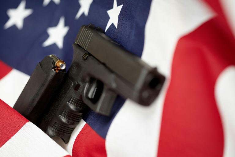 Hand Gun Pistol with loaded magazine on top of the American flag