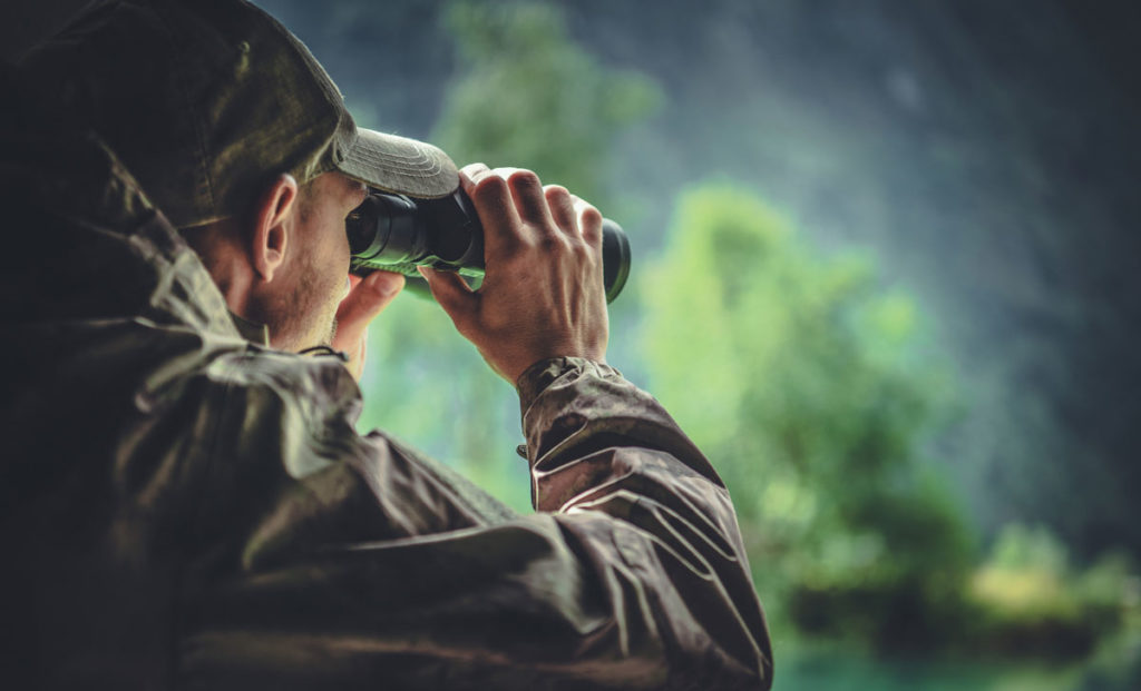 Hunter Man using binoculars to spot deer