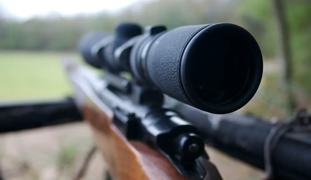 A rifle in a deer stand with a scope