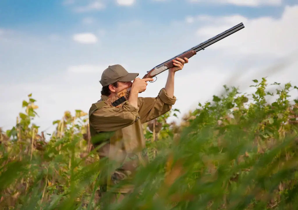 Hunter holding a shotgun for shooting birds in the sky