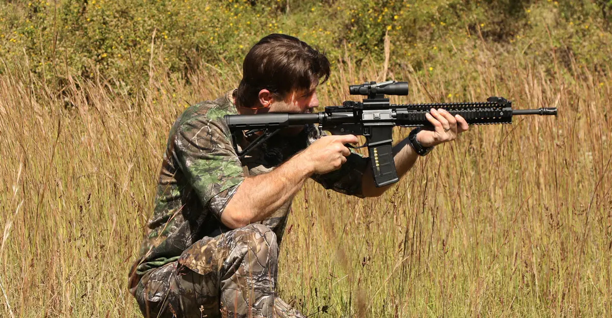 Man hunting in camo with an AR-15 Rifle