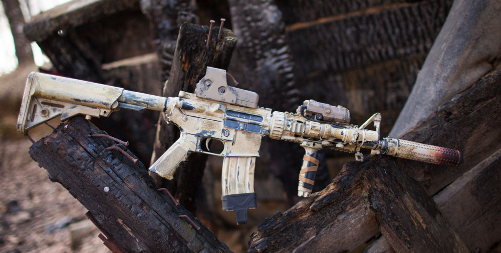 AR15 with tan paint job sitting on logs