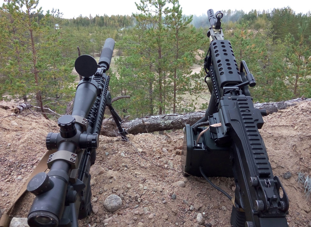 Assault rifle and machine gun sitting on a dirt hill