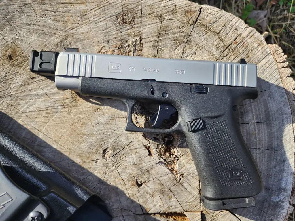 Glock 48 slimline pistol 9mm sitting on a log