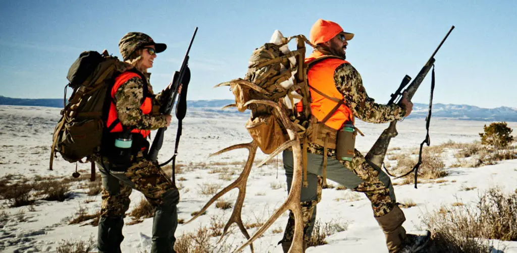 Two hunters carrying big antlers hunting with the Mossberg Patriot rifle