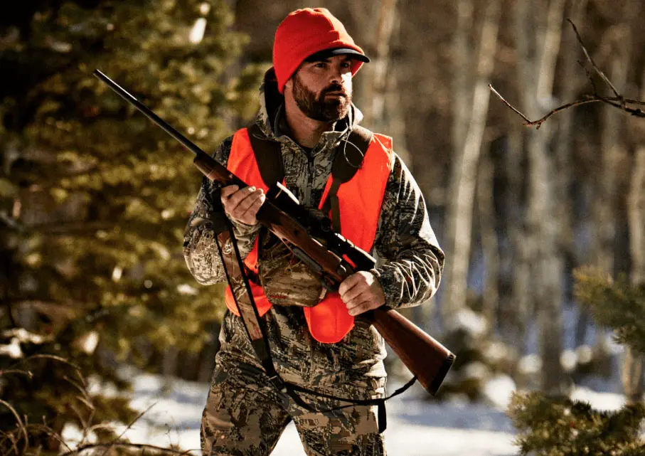 Mossberg Patriot held by man hunting in snow with camo clothes