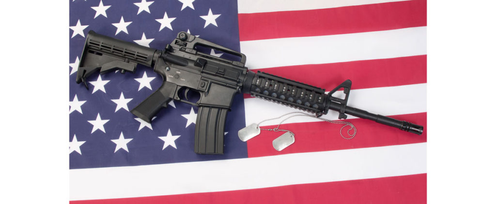 AR15 Rifle laying on an American flag with military dog tags beside it