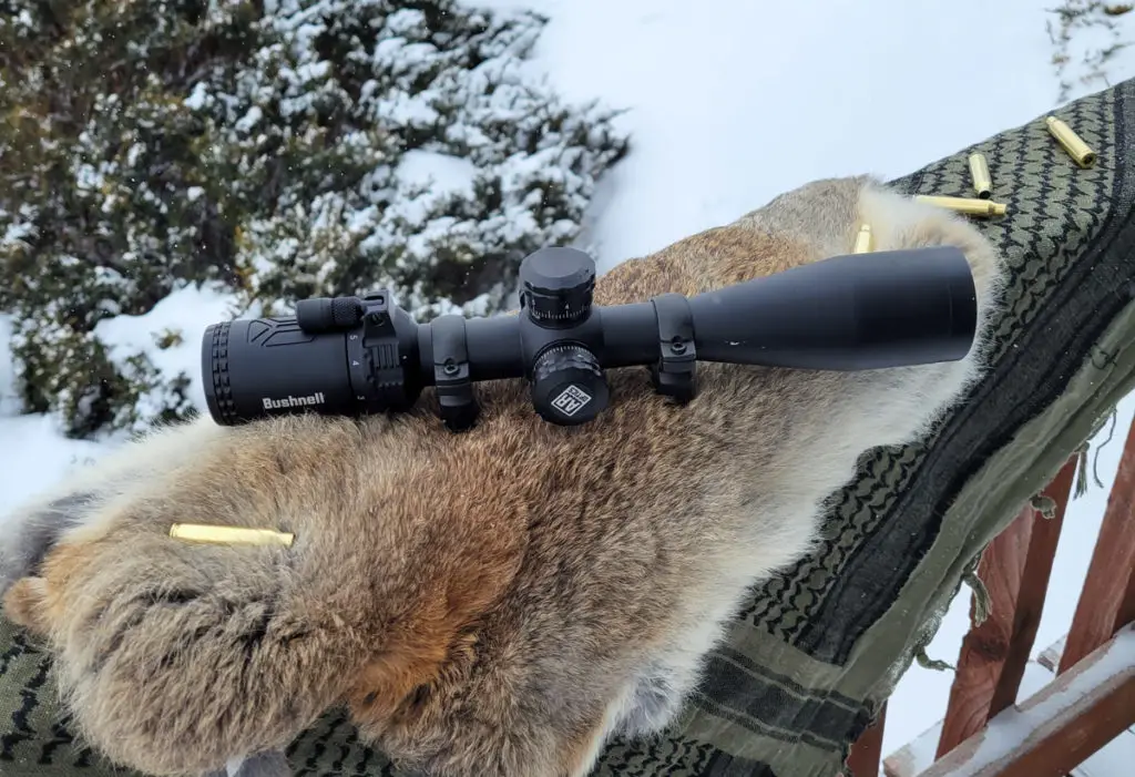 Bushnell AR Scope sitting on animal skin with rifle ammo beside it