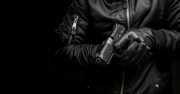 Man dressed in all black holding a firearm
