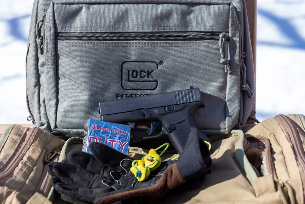 Glock 43 next to a bag with gloves and ear plugs