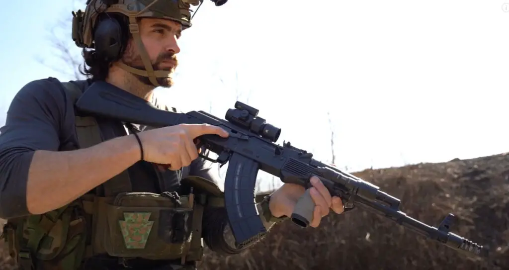 Man holds rifle which has a Vortex Strikefire 2 mounted on top of it