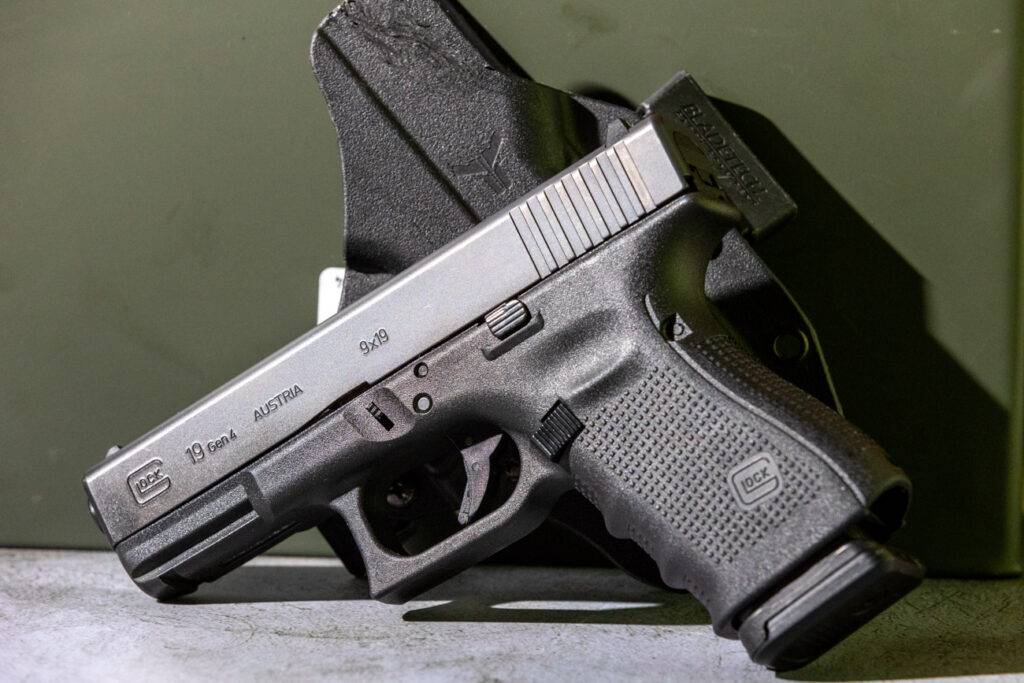 Glock 19 pistol sitting on its side in front of holster