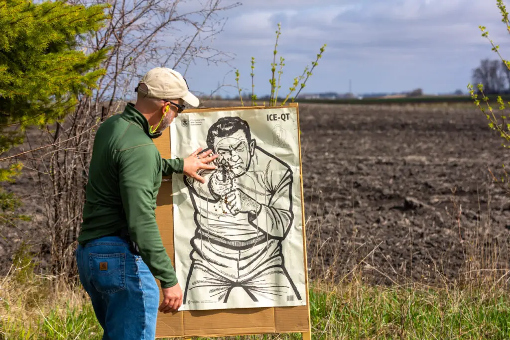 Man inspecting target after shooting glock 19 and 43 at it