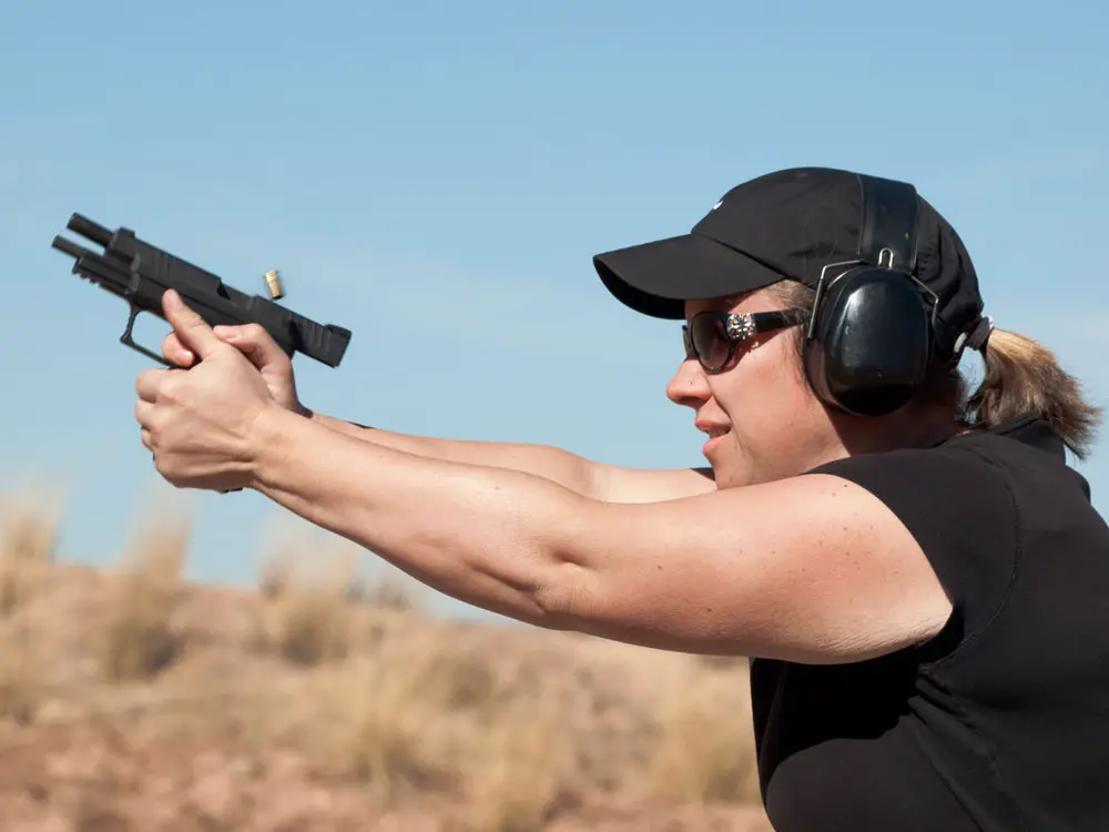 Woman shooting a pistol at an outdoor gun range