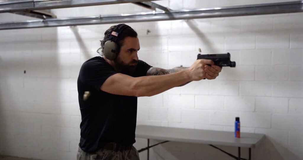 Man at an indoor gun range firing the PSA Dagger