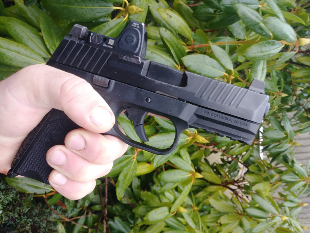 Man holding the FN 509 pistol aiming